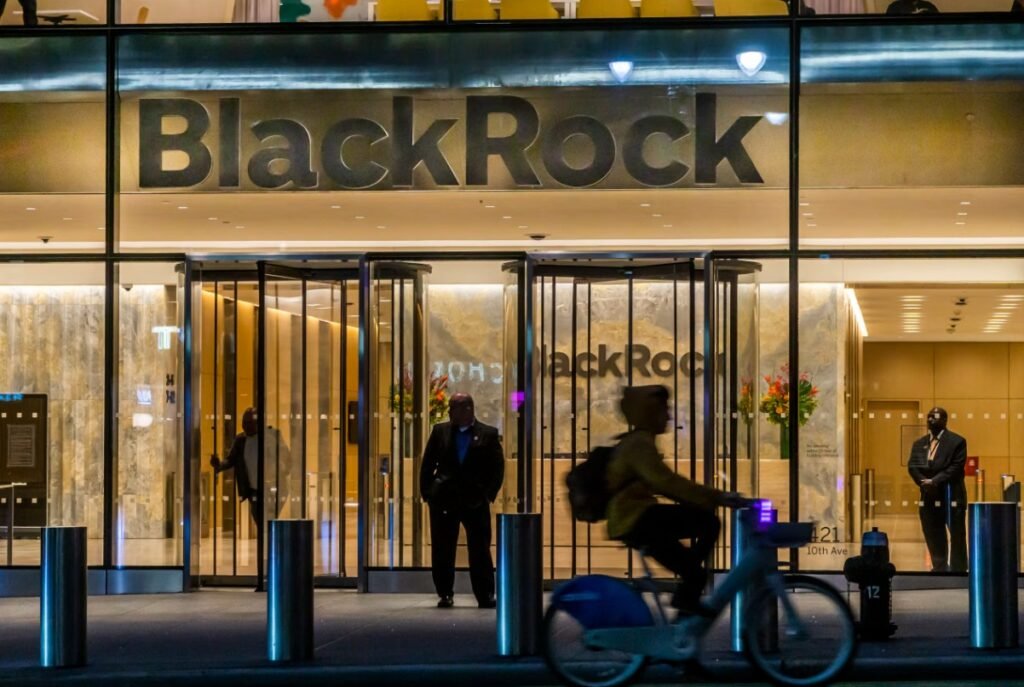 BlackRock headquarters entrance with illuminated company logo and person cycling past
